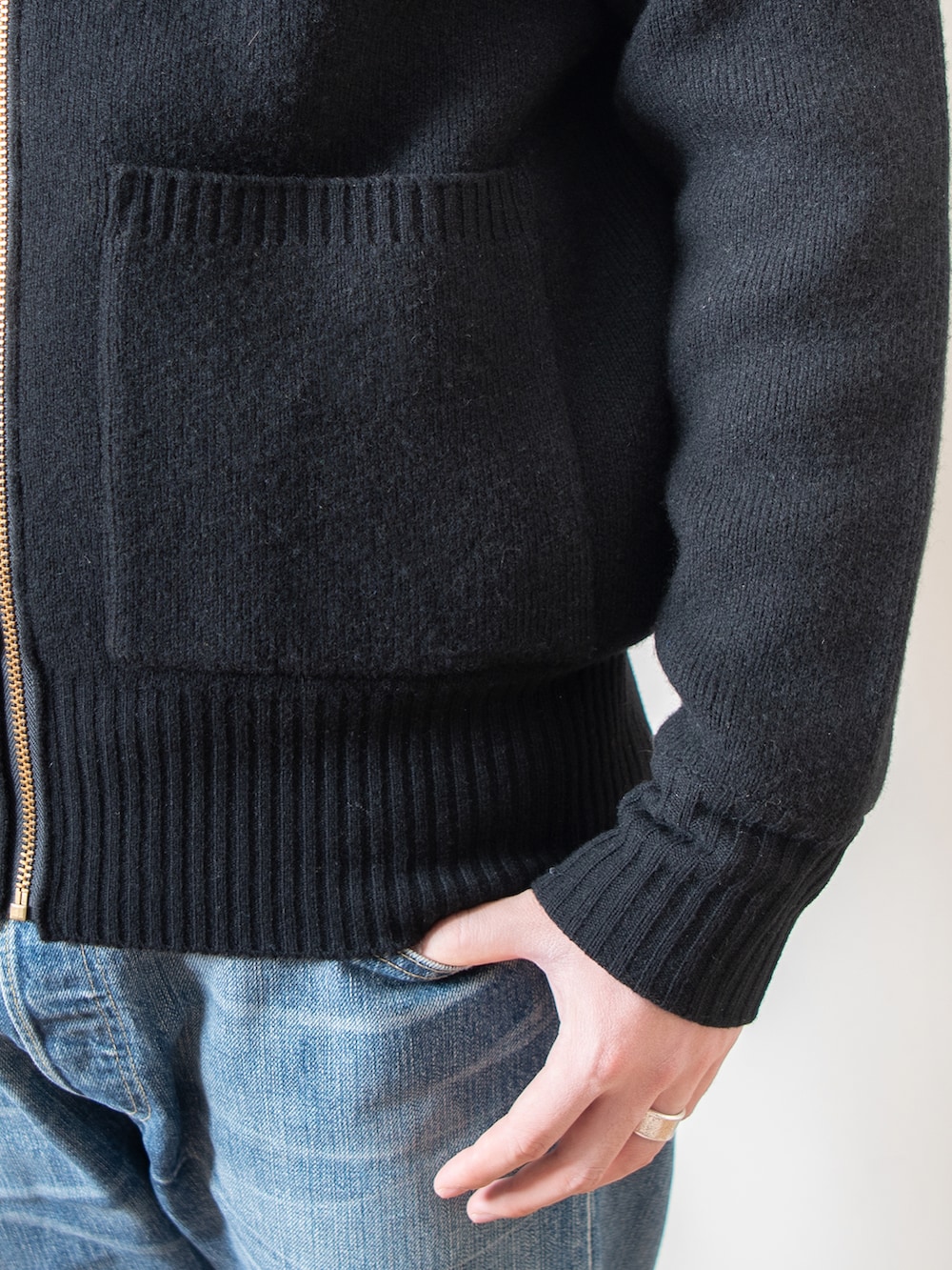 ブルー系のデニムパンツ、ブラック系のニット/セーター、ベージュ系のステンカラーコートを着用したメンズの春コーディネートの4枚目の写真