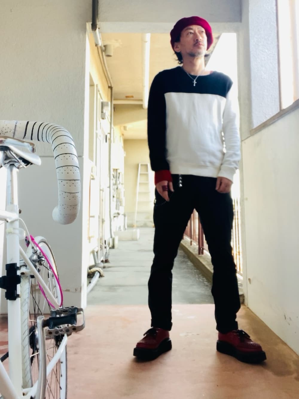 ブラック系のニット/セーター、ブラック系のチノパンツ、レッド系のブーツを着用したメンズの春コーディネートの3枚目の写真