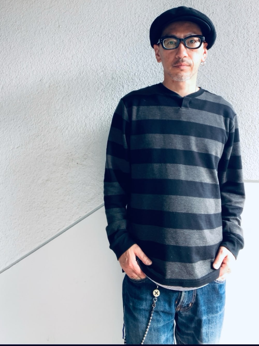 グレー系のニット/セーター、ブルー系のデニムパンツ、ブラック系のサンダルを着用したメンズの春コーディネートの2枚目の写真