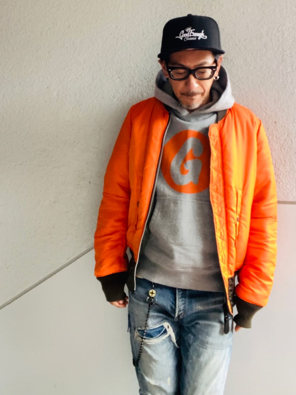 グレー系のパーカー、グレー系のMA-1、ブルー系のデニムパンツを着用したメンズの冬コーディネートの2枚目の写真