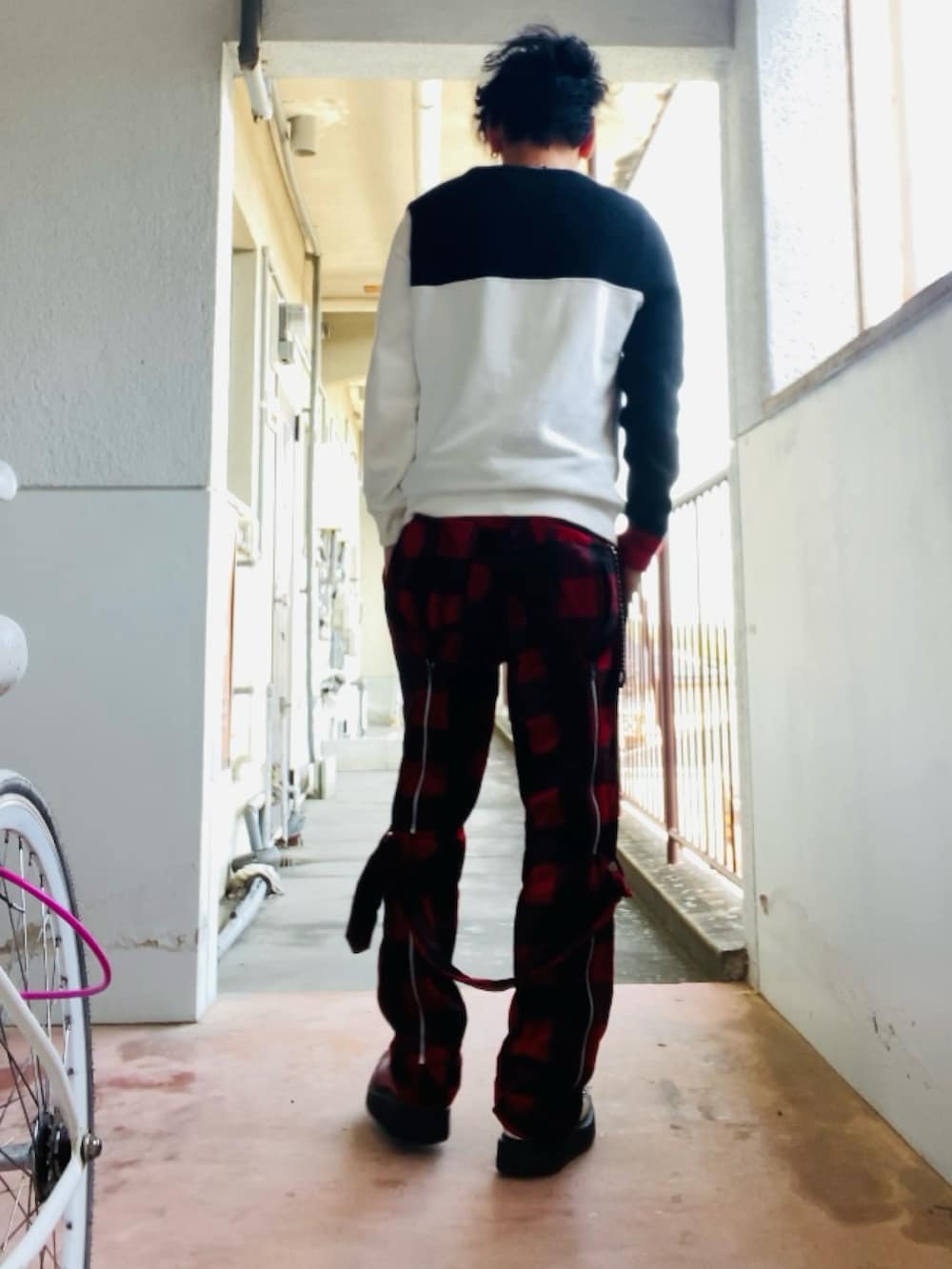 ブラック系のニット/セーター、レッド系のその他パンツ、レッド系のブーツを着用したメンズの春コーディネートの3枚目の写真