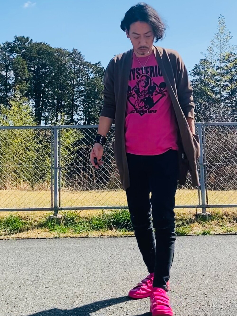 ピンク系のTシャツ/カットソー、ブラウン系のニット/セーター、ブラック系のデニムパンツを着用したメンズの春コーディネートの2枚目の写真