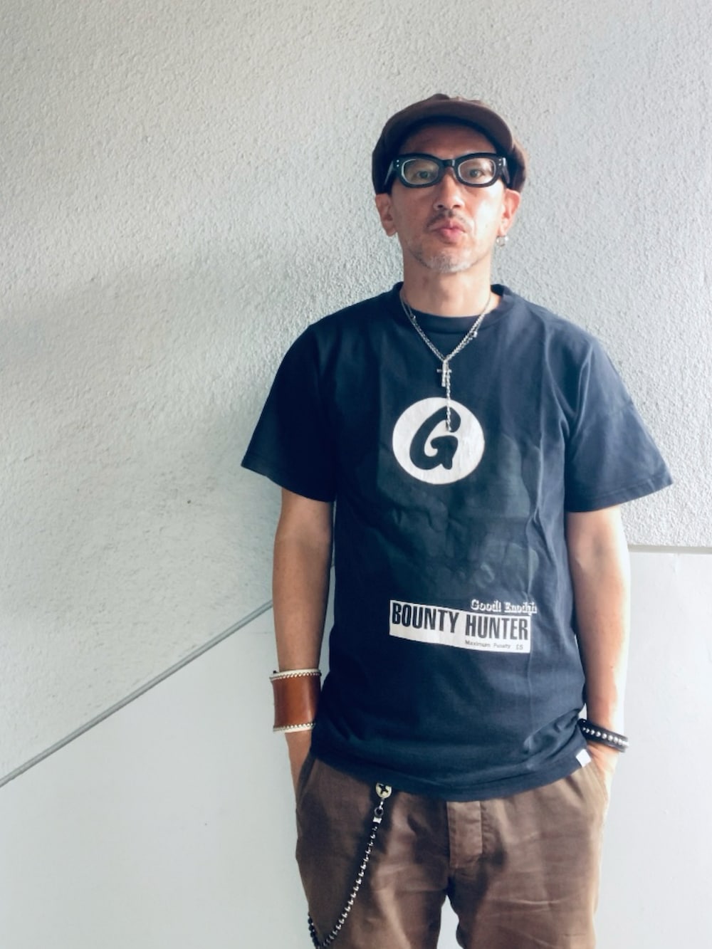 ブラウン系のチノパンツ、ブラック系のTシャツ/カットソー、ブラック系のスリッポンを着用したメンズの夏コーディネートの3枚目の写真