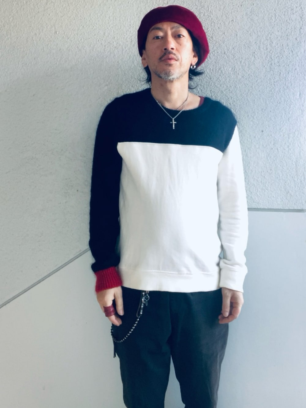 ブラック系のニット/セーター、ブラック系のチノパンツ、レッド系のブーツを着用したメンズの春コーディネートの2枚目の写真