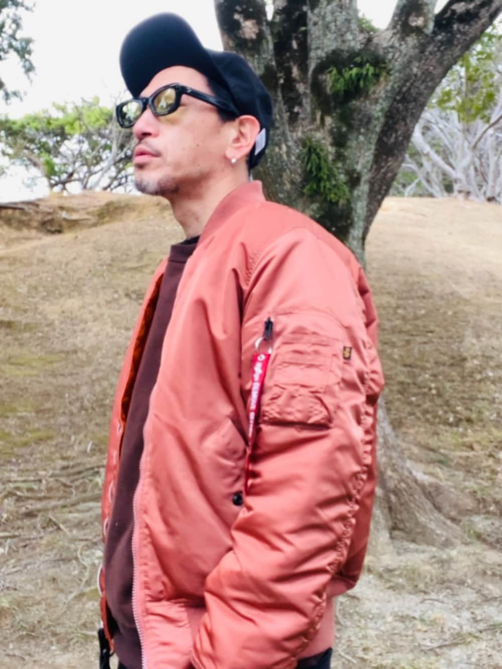 レッド系のMA-1、ブラウン系のスウェット、ブラック系のその他パンツを着用したメンズの冬コーディネートの2枚目の写真