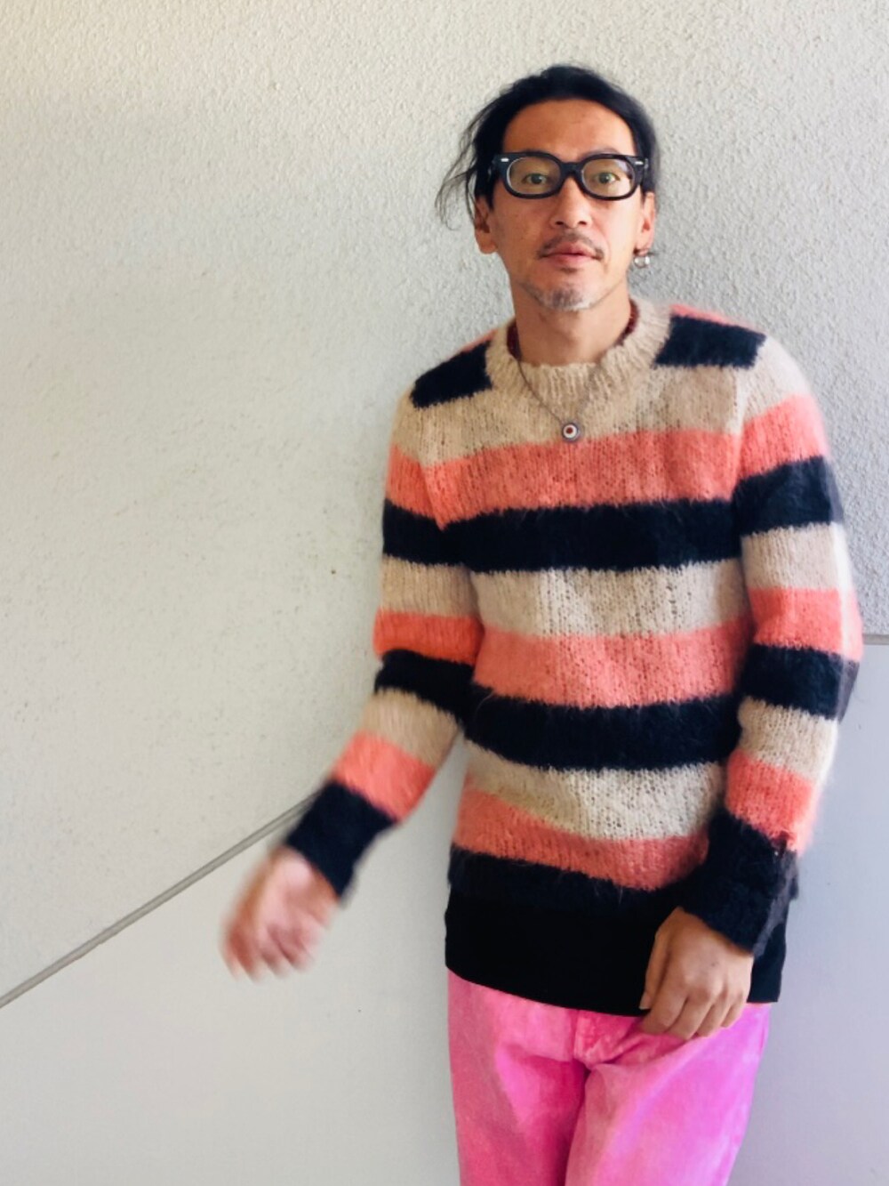 ピンク系のニット/セーター、ピンク系のデニムパンツ、ブラック系のスニーカーを着用したメンズの秋コーディネートの5枚目の写真