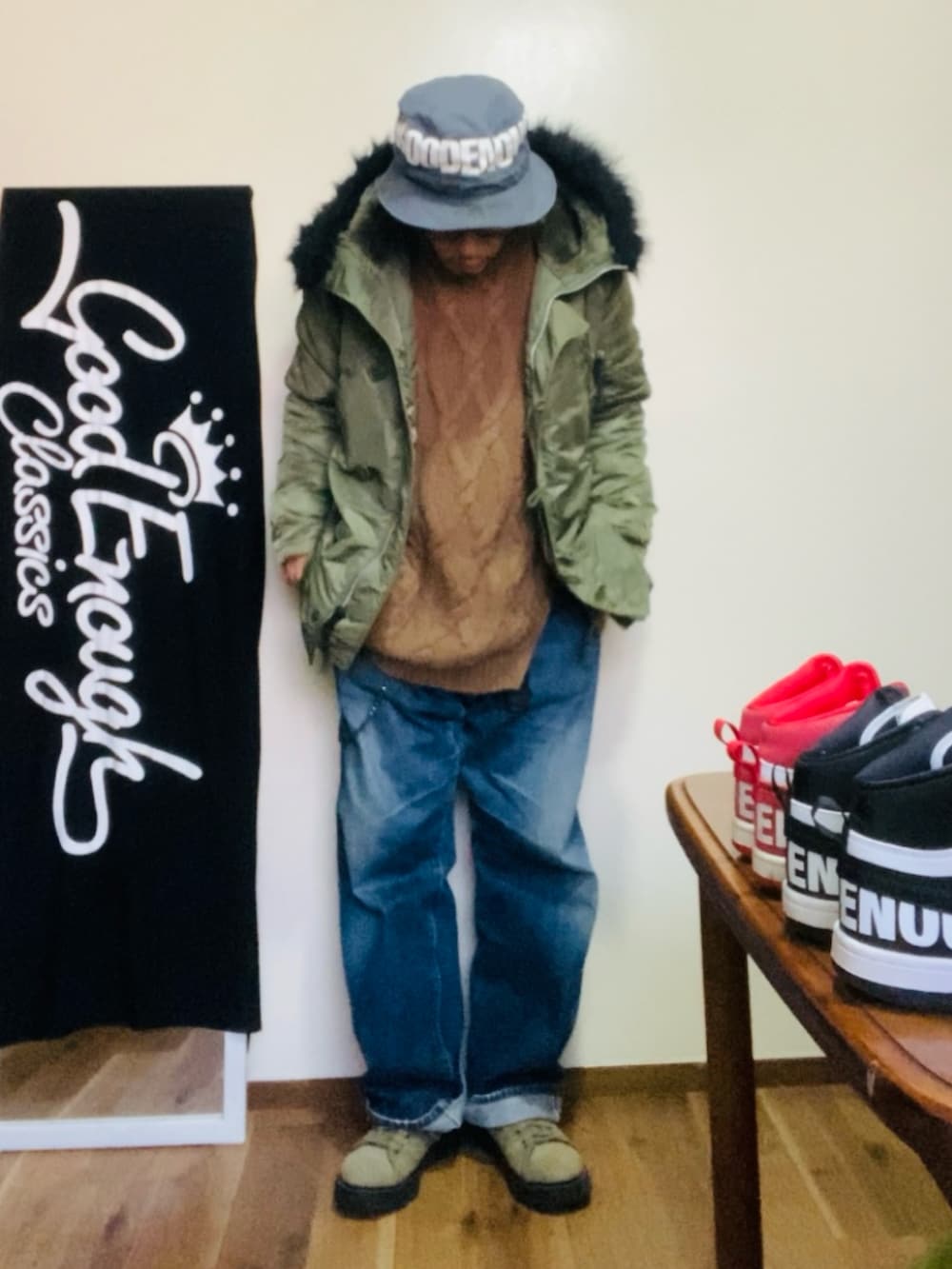 グリーン系のミリタリージャケット、ブラウン系のニット/セーター、ブルー系のデニムパンツを着用したメンズの冬コーディネートの2枚目の写真