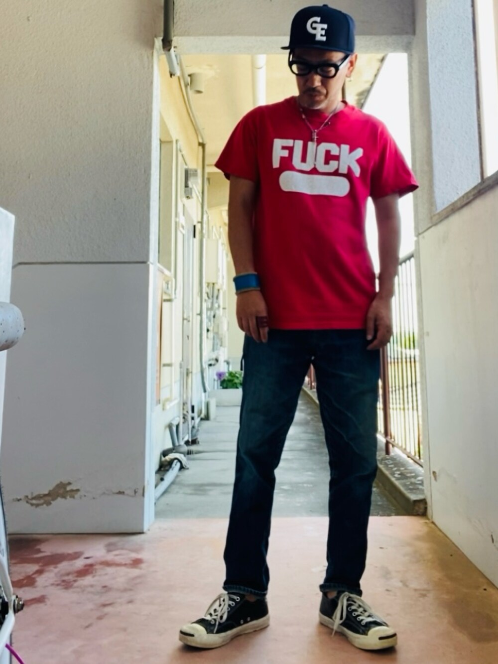 レッド系のTシャツ/カットソー、ブルー系のデニムパンツ、ブラック系のスニーカーを着用したメンズの夏コーディネートの2枚目の写真