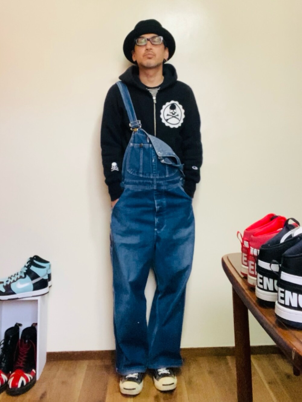 ブラック系のパーカー、ブルー系のサロペット/オーバーオール、ブラック系のスニーカーを着用したメンズの春コーディネートの2枚目の写真