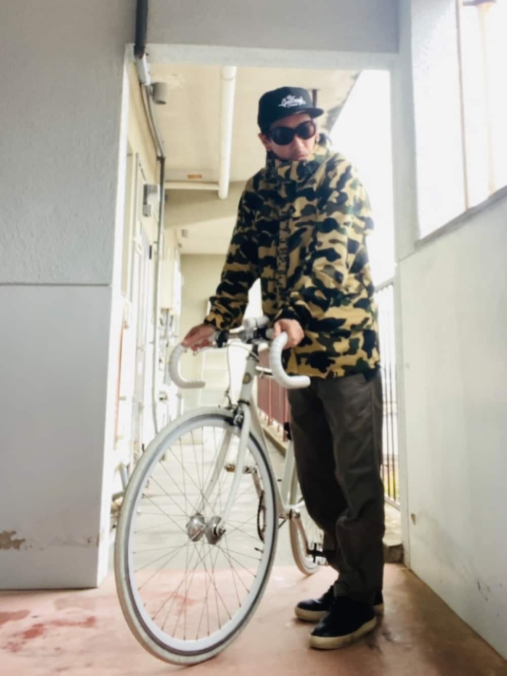 イエロー系のマウンテンパーカー、ブラウン系のチノパンツ、ブラック系のキャップを着用したメンズの秋コーディネートの3枚目の写真
