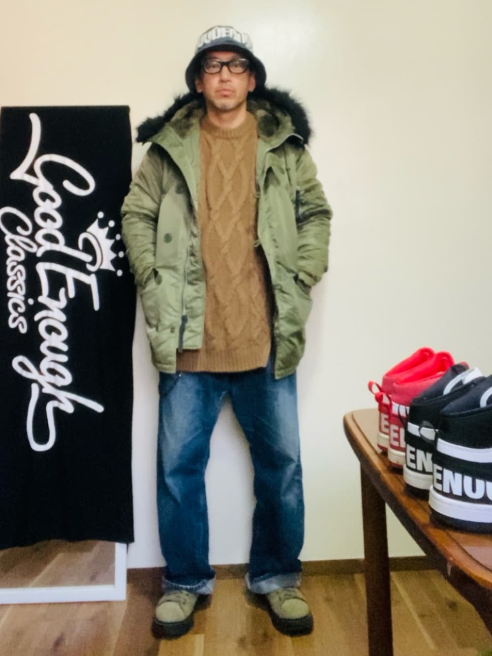 グリーン系のミリタリージャケット、ブラウン系のニット/セーター、ブルー系のデニムパンツを着用したメンズの冬コーディネートの3枚目の写真