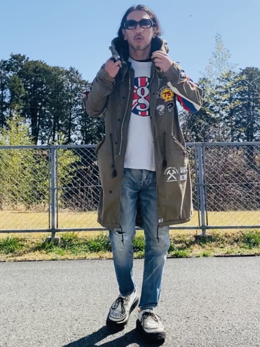 グリーン系のモッズコート、ホワイト系のTシャツ/カットソー、ブルー系のデニムパンツを着用したメンズの秋コーディネートの3枚目の写真