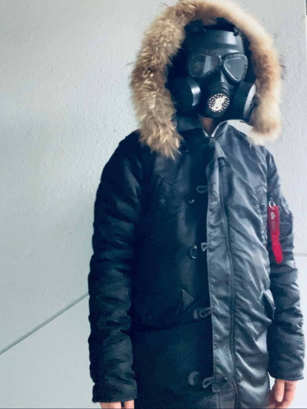 ブラック系のミリタリージャケット、ピンク系のニット/セーター、グレー系のパンツを着用したメンズの冬コーディネートの3枚目の写真