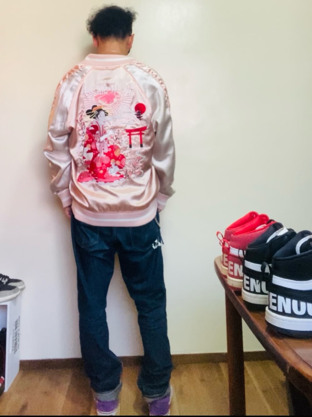 パープル系のスニーカー、ピンク系のスカジャン、ブルー系のデニムパンツを着用したメンズの秋コーディネートの3枚目の写真