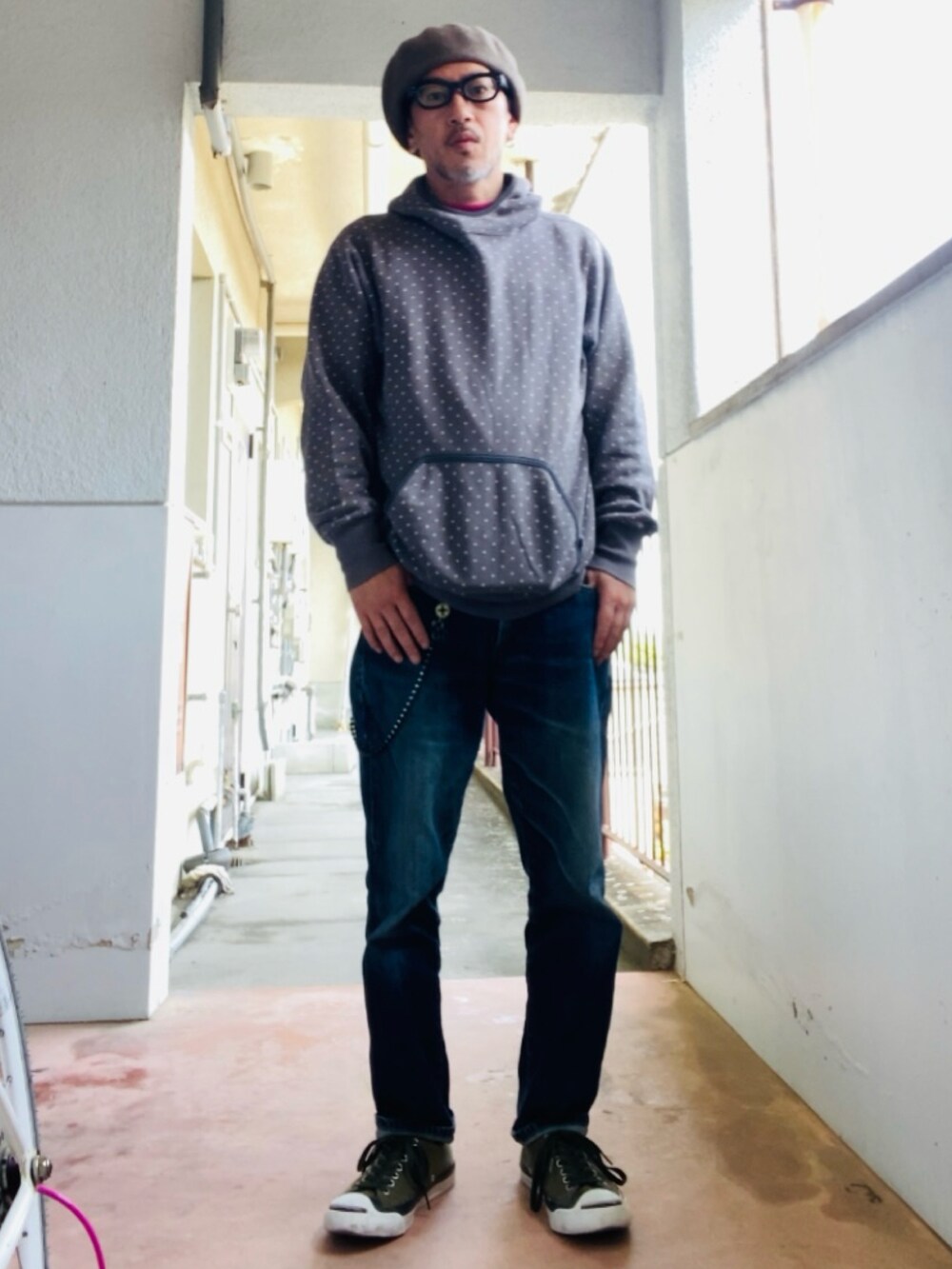 グレー系のパーカー、ブルー系のデニムパンツ、グリーン系のスニーカーを着用したメンズの春コーディネートの3枚目の写真