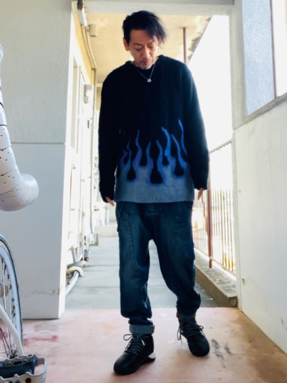 ブラック系のニット/セーター、ブルー系のデニムパンツ、ブラック系のスニーカーを着用したメンズの秋コーディネートの3枚目の写真