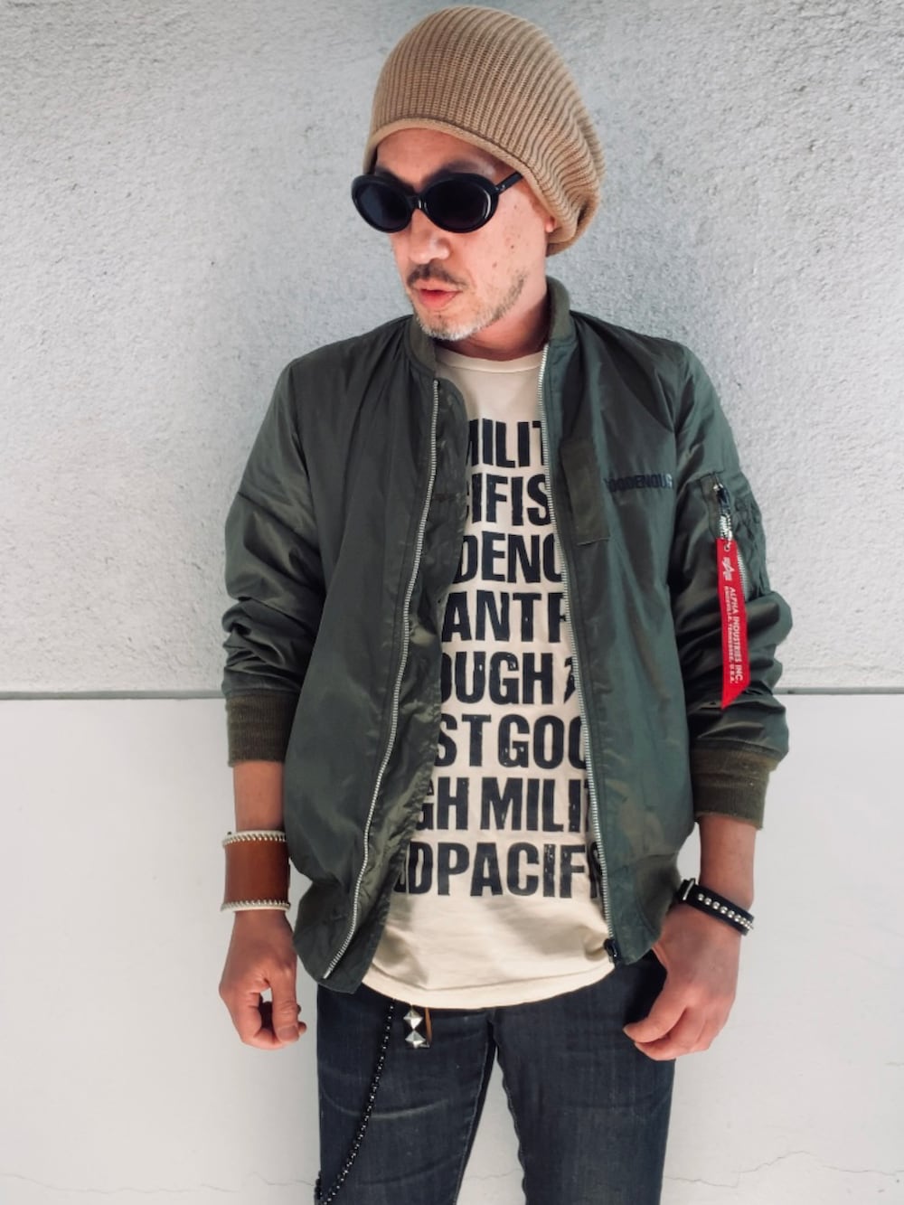 グリーン系のMA-1、ベージュ系のTシャツ/カットソー、ブラック系のデニムパンツを着用したメンズの春コーディネートの2枚目の写真
