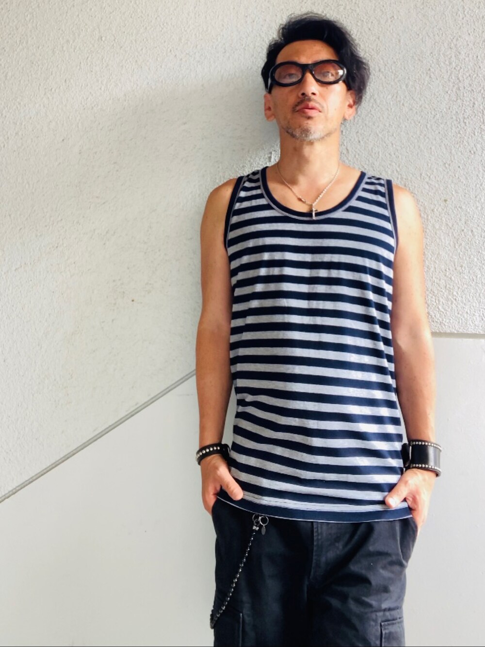 グレー系のタンクトップ、ブラック系のカーゴパンツ、ブラック系のサンダルを着用したメンズの夏コーディネートの4枚目の写真