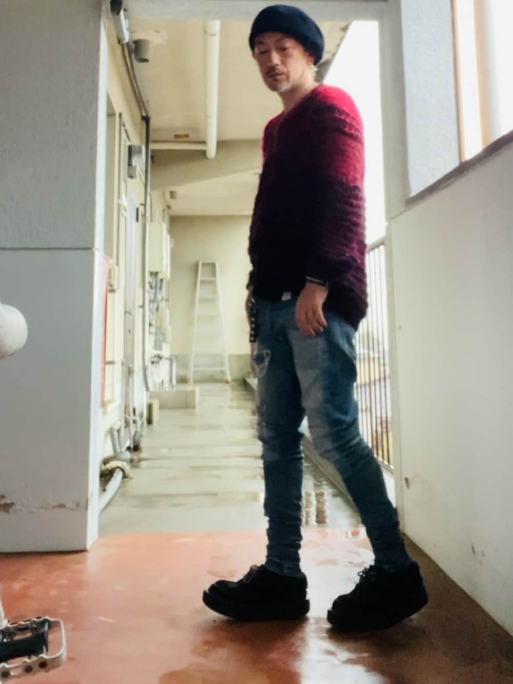 レッド系のニット/セーター、ブラック系のタンクトップ、ブルー系のデニムパンツを着用したメンズの春コーディネートの5枚目の写真