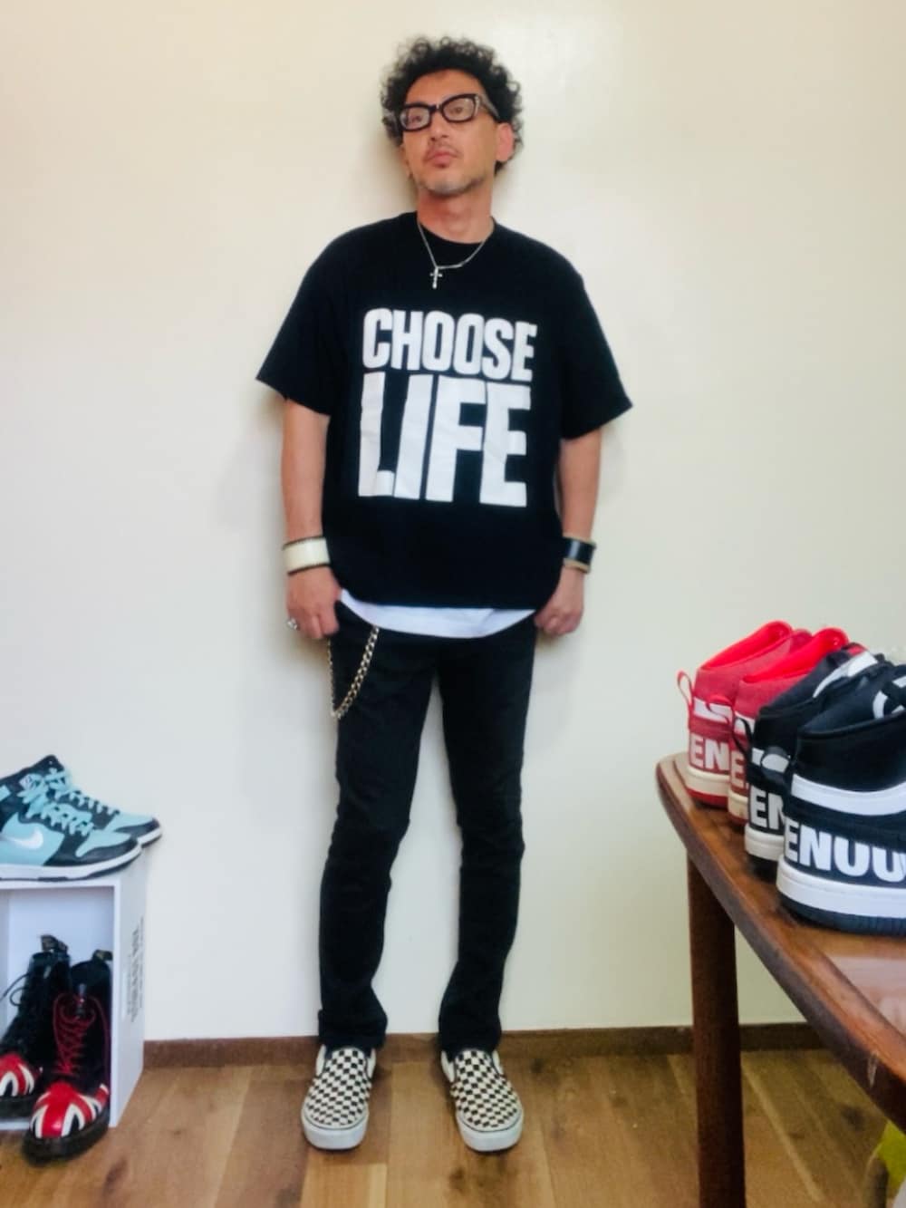 ブラック系のTシャツ/カットソー、ブラック系のパンツ、ホワイト系のスリッポンを着用したメンズの夏コーディネートの2枚目の写真