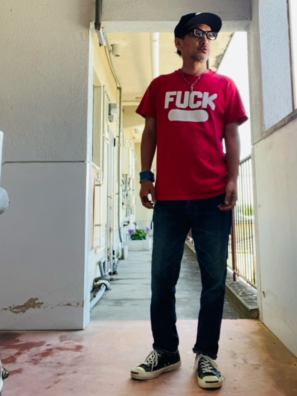 レッド系のTシャツ/カットソー、ブルー系のデニムパンツ、ブラック系のスニーカーを着用したメンズの夏コーディネートの4枚目の写真