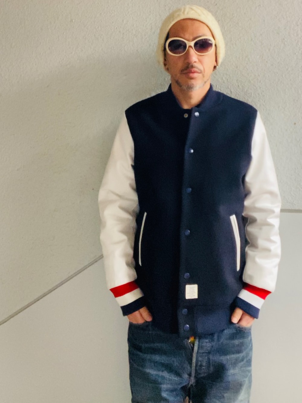 ブラック系のスタジャン、ブルー系のデニムパンツ、ホワイト系のスニーカーを着用したメンズの冬コーディネートの2枚目の写真