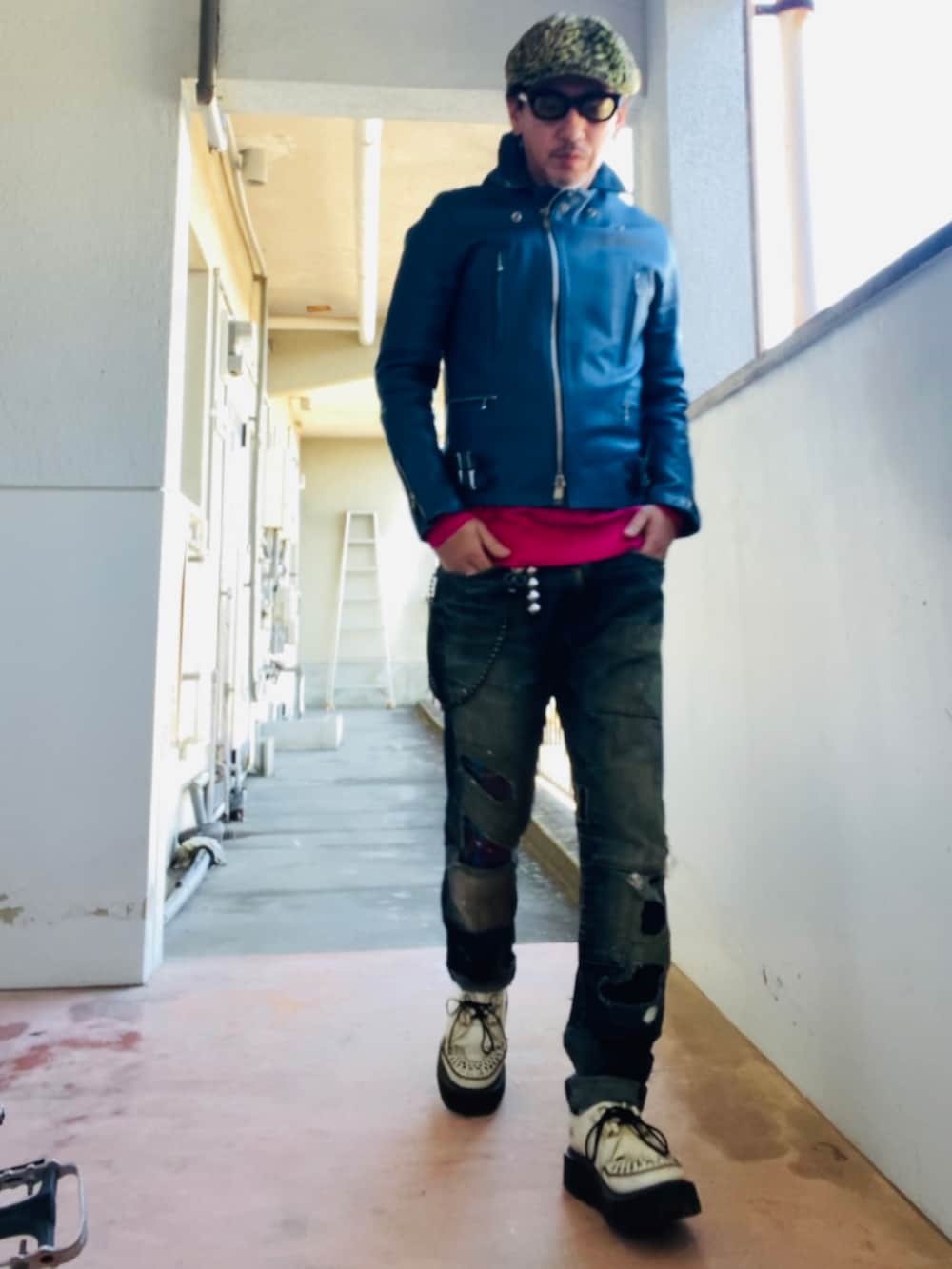 ブルー系のライダースジャケット、ピンク系のニット/セーター、ブルー系のデニムパンツを着用したメンズの冬コーディネートの2枚目の写真