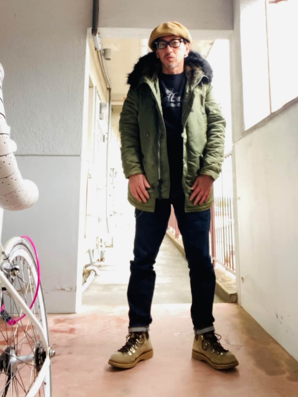 グリーン系のミリタリージャケット、ブラック系のスウェット、ブルー系のデニムパンツを着用したメンズの冬コーディネートの3枚目の写真