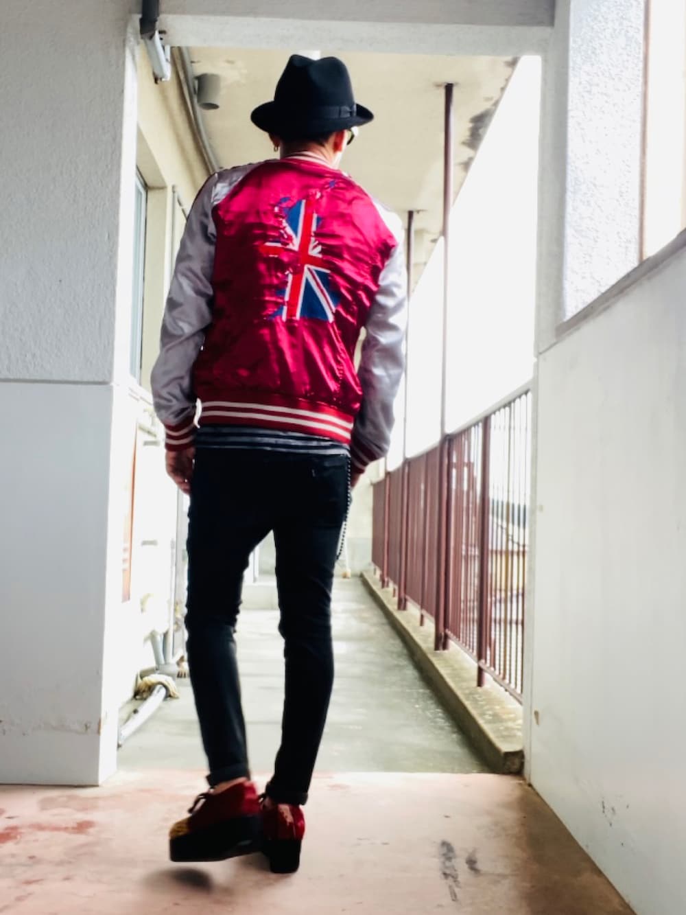 レッド系のスカジャン、ブラック系のタンクトップ、ブラック系のデニムパンツを着用したメンズの秋コーディネートの2枚目の写真