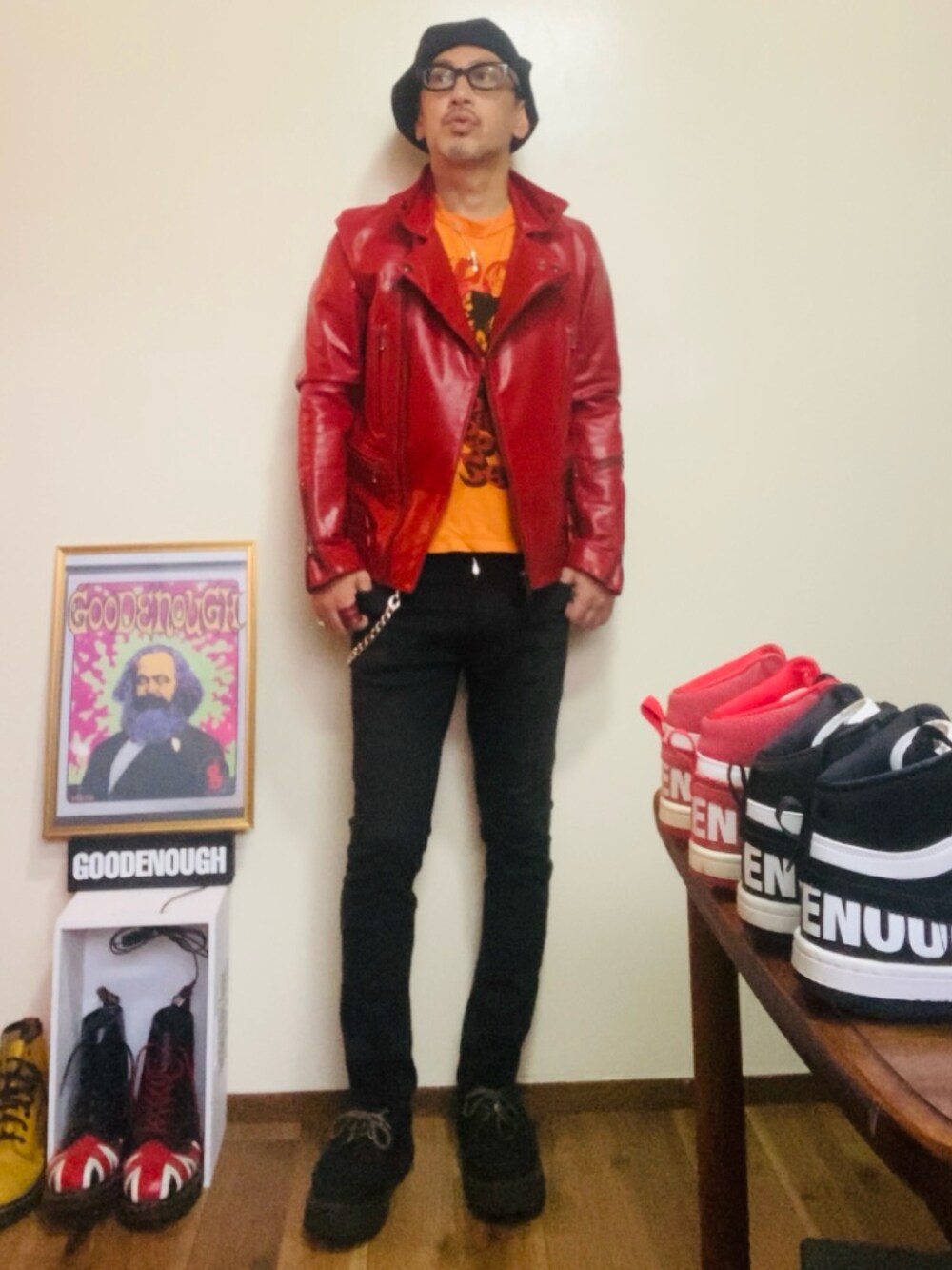 レッド系のライダースジャケット、オレンジ系のTシャツ/カットソー、ブラック系のパンツを着用したメンズの秋コーディネートの2枚目の写真