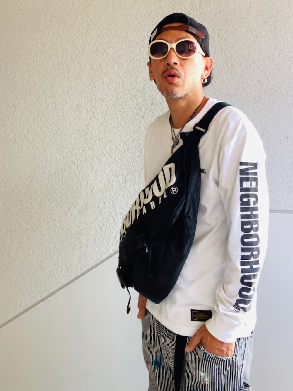 ホワイト系のTシャツ/カットソー、ブラック系のメッセンジャーバッグ、グレー系のデニムパンツを着用したメンズの秋コーディネートの2枚目の写真