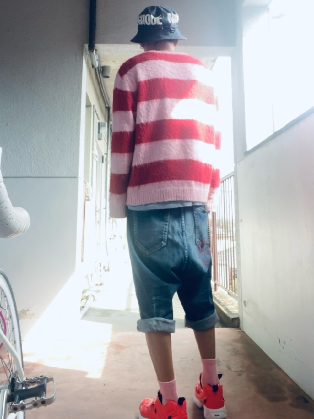ブルー系のデニムパンツ、ピンク系のニット/セーター、ピンク系のスニーカーを着用したメンズの春コーディネートの3枚目の写真