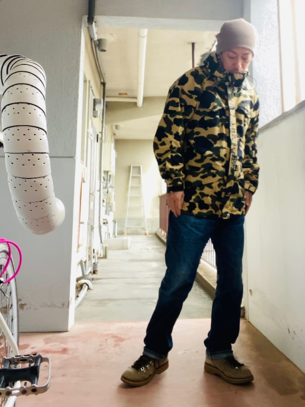 イエロー系のマウンテンパーカー、ブルー系のデニムパンツ、ベージュ系のブーツを着用したメンズの秋コーディネートの5枚目の写真