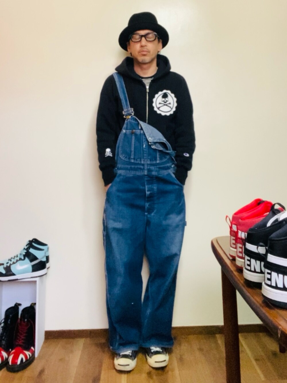 ブラック系のパーカー、ブルー系のサロペット/オーバーオール、ブラック系のスニーカーを着用したメンズの春コーディネートの3枚目の写真