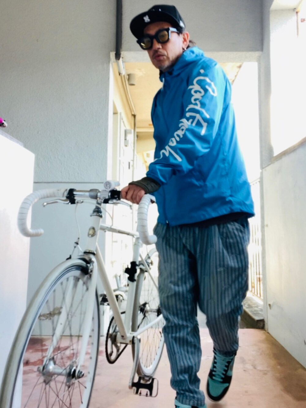 ブルー系のナイロンジャケット、ブルー系のデニムパンツ、グリーン系のスニーカーを着用したメンズの冬コーディネートの4枚目の写真