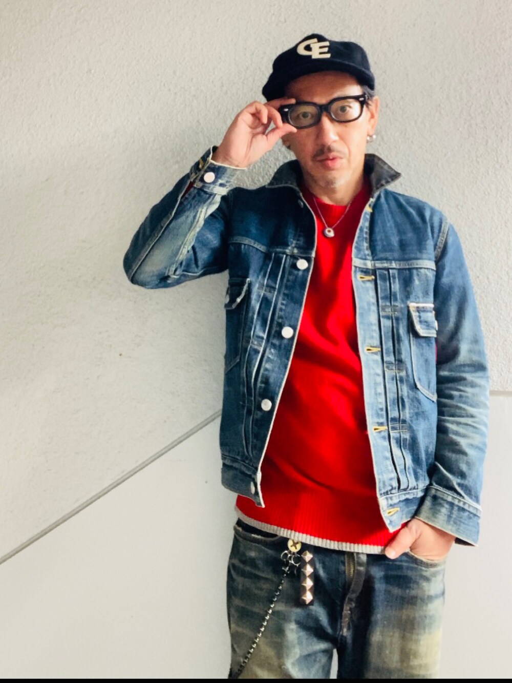 ブルー系のデニムジャケット、レッド系のニット/セーター、ブルー系のデニムパンツを着用したメンズの冬コーディネートの2枚目の写真