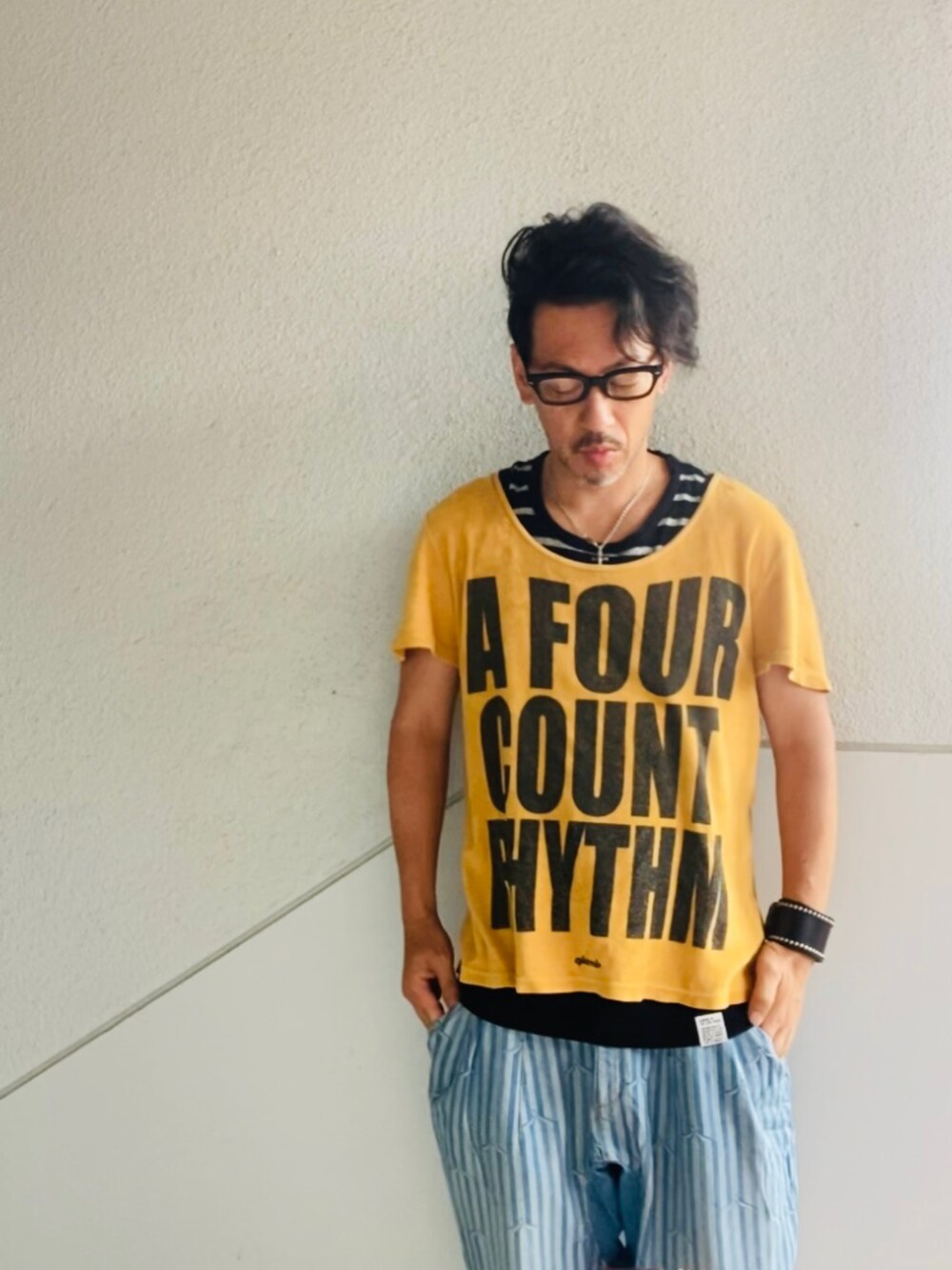 ゴールド系のTシャツ/カットソー、ブルー系のデニムパンツ、ブラック系のサンダルを着用したメンズの夏コーディネートの4枚目の写真