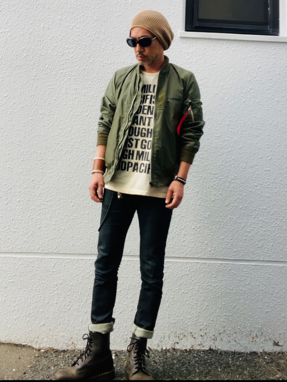 グリーン系のMA-1、ベージュ系のTシャツ/カットソー、ブラック系のデニムパンツを着用したメンズの春コーディネートの5枚目の写真