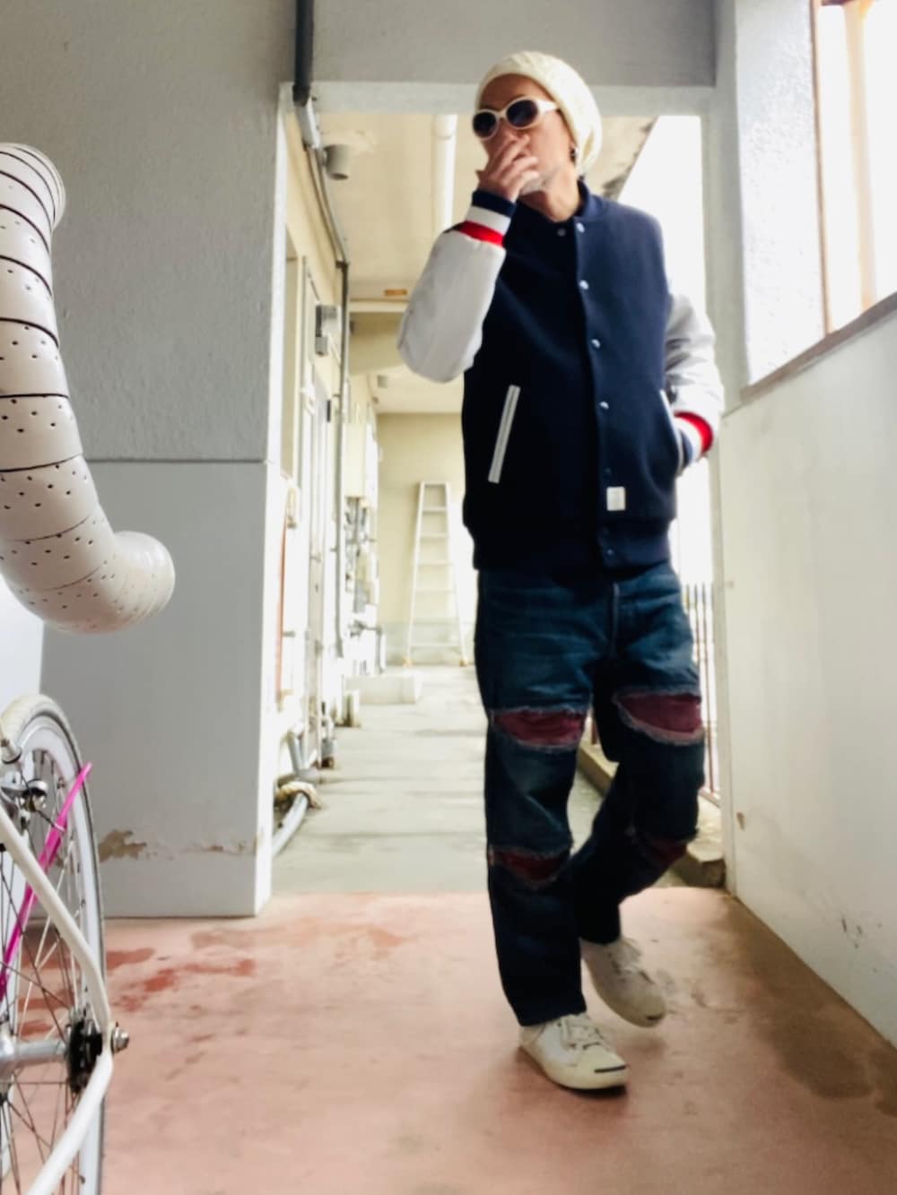 ブラック系のスタジャン、ブルー系のデニムパンツ、ホワイト系のスニーカーを着用したメンズの冬コーディネートの3枚目の写真