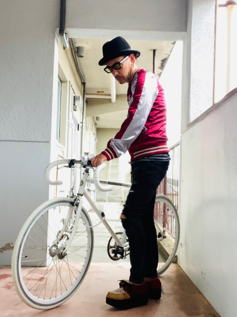 レッド系のスカジャン、ブラック系のタンクトップ、ブラック系のデニムパンツを着用したメンズの秋コーディネートの4枚目の写真