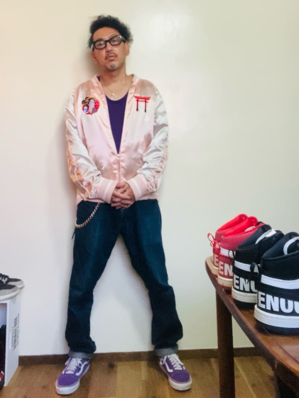 パープル系のスニーカー、ピンク系のスカジャン、ブルー系のデニムパンツを着用したメンズの秋コーディネートの2枚目の写真