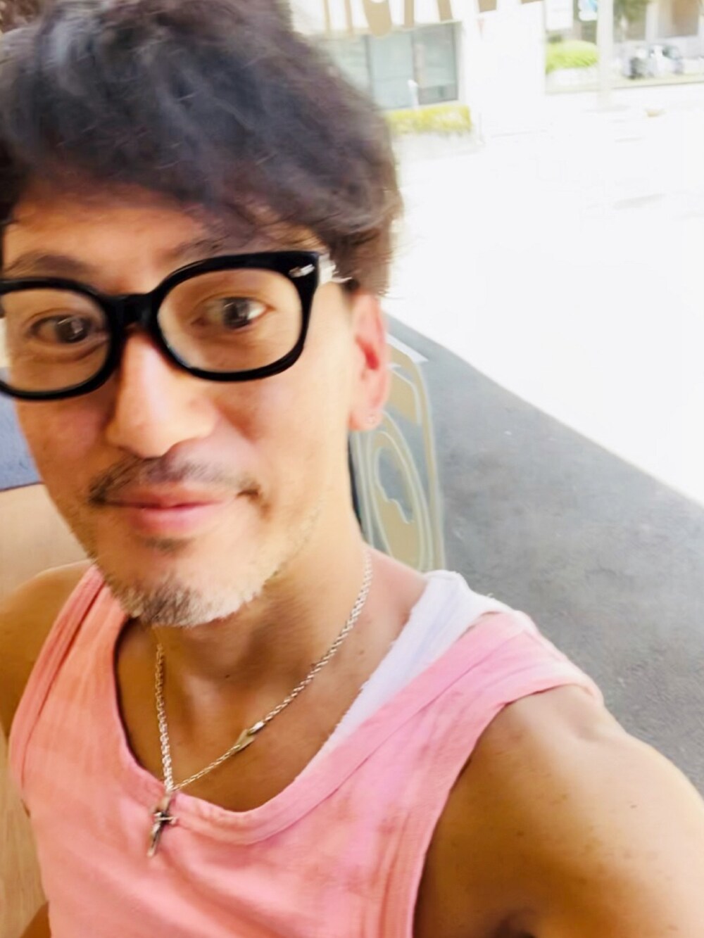 ピンク系のタンクトップ、ブルー系のデニムパンツ、ピンク系のスニーカーを着用したメンズの夏コーディネートの4枚目の写真