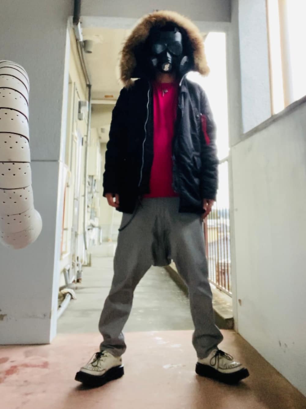 ブラック系のミリタリージャケット、ピンク系のニット/セーター、グレー系のパンツを着用したメンズの冬コーディネートの2枚目の写真