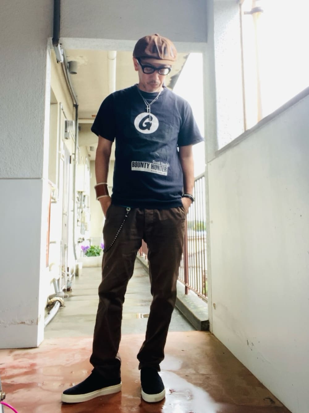 ブラウン系のチノパンツ、ブラック系のTシャツ/カットソー、ブラック系のスリッポンを着用したメンズの夏コーディネートの5枚目の写真