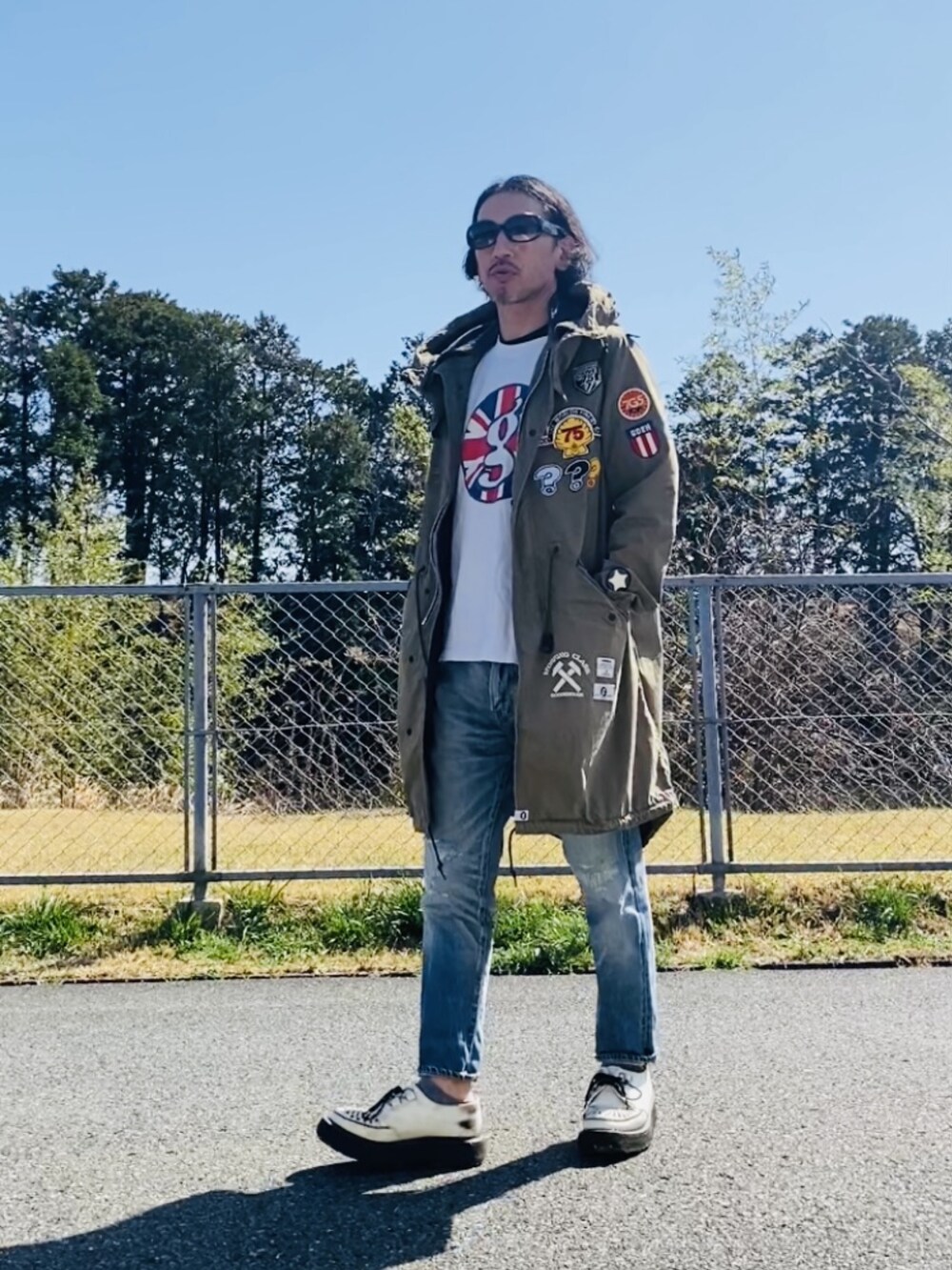 グリーン系のモッズコート、ホワイト系のTシャツ/カットソー、ブルー系のデニムパンツを着用したメンズの秋コーディネートの5枚目の写真