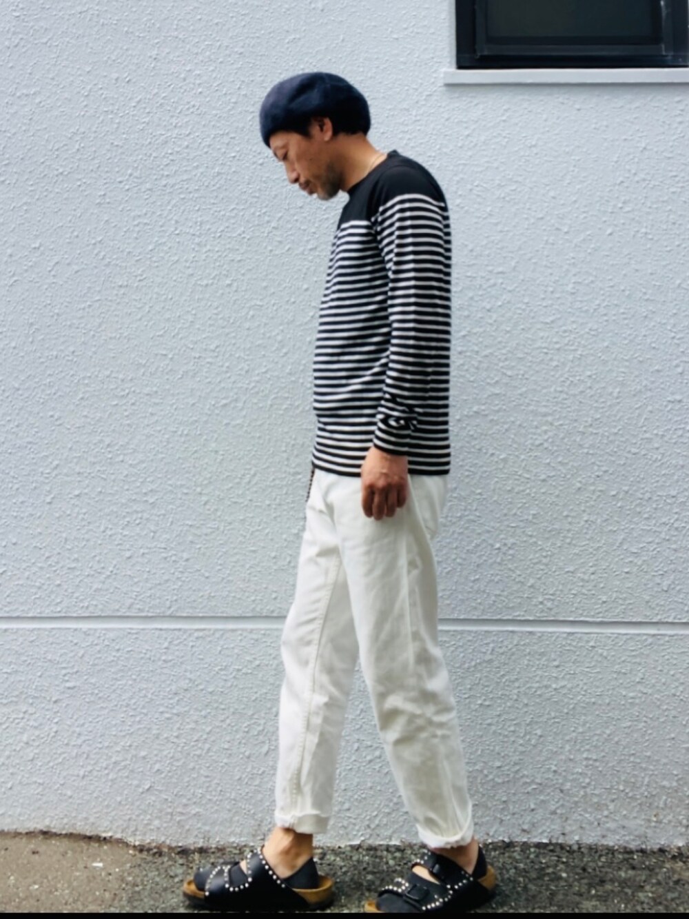 ブラック系のニット/セーター、ホワイト系のデニムパンツ、ブラック系のサンダルを着用したメンズの夏コーディネートの3枚目の写真