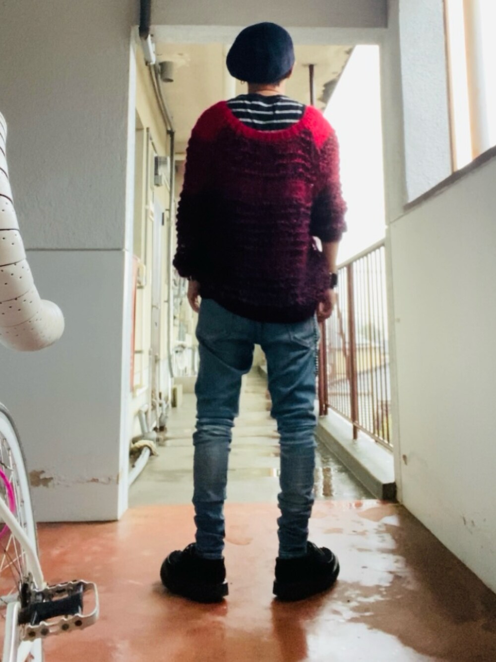 レッド系のニット/セーター、ブラック系のタンクトップ、ブルー系のデニムパンツを着用したメンズの春コーディネートの3枚目の写真