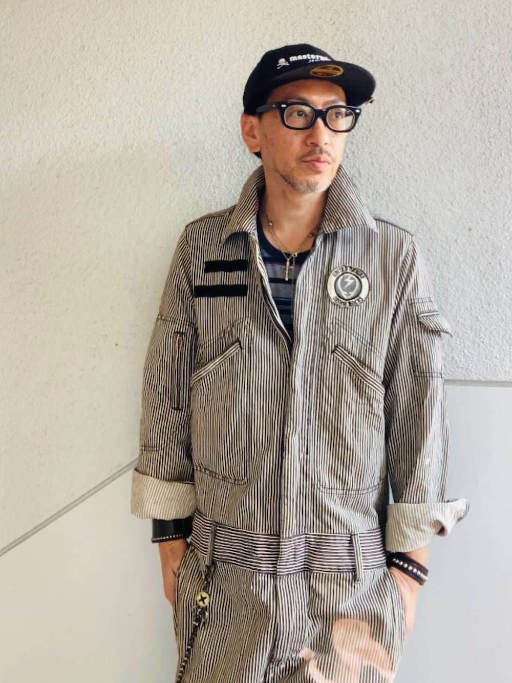 グレー系のつなぎ/オールインワン、ブラック系のスニーカー、ブラック系のキャップを着用したメンズの春コーディネートの5枚目の写真