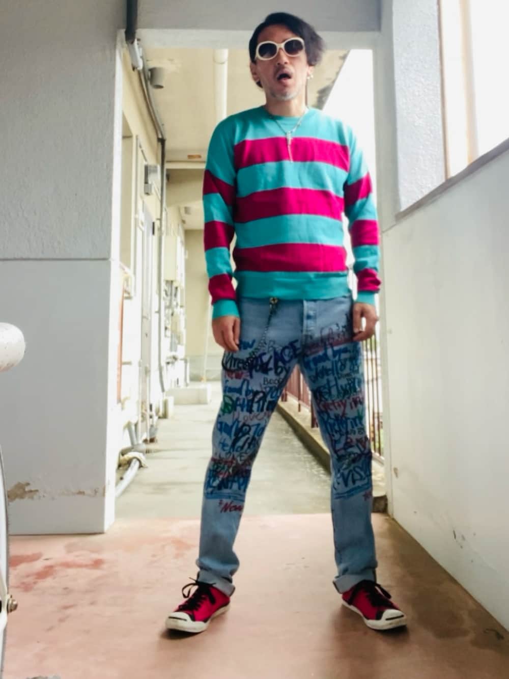 グリーン系のニット/セーター、ブルー系のデニムパンツ、ピンク系のスニーカーを着用したメンズの春コーディネートの5枚目の写真