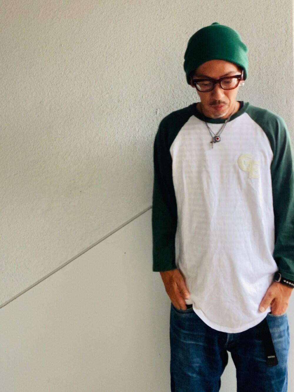 グリーン系のTシャツ/カットソー、ブルー系のデニムパンツ、グリーン系のスニーカーを着用したメンズの秋コーディネートの5枚目の写真